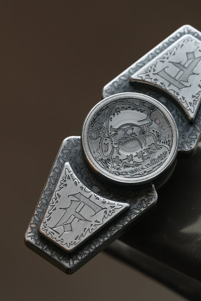 Close-up of a detailed metal accessory featuring intricate engraved designs on a neutral background.